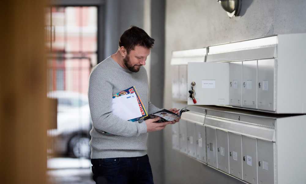 A man looking through his mail while standing next to his mailbox