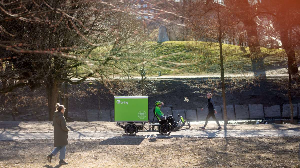 Varesykkel med Bring-container sykles av Bring-sjåfør. Høstbilde fra Akerselva i Oslo.