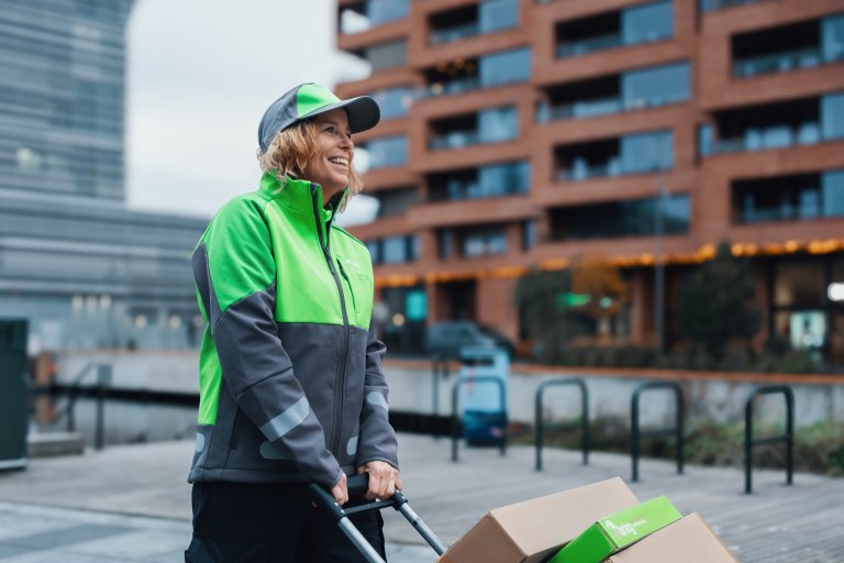 En kvinnelig Bringbud trekker en vogn med pakker på gjennom byen